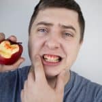 man with bleeding gums holding an apple